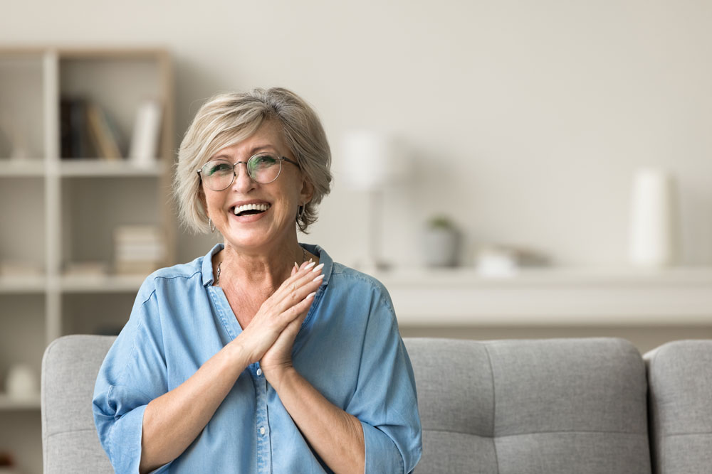 Senhora sorrindo, feliz e em segurança dentro de sua casa