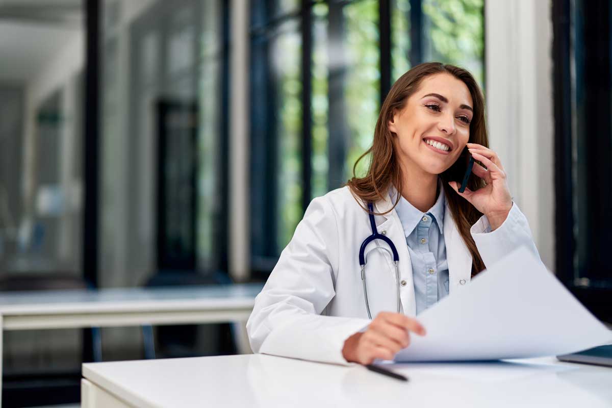 Médica em seu consultório falando ao telefone com seu paciente.